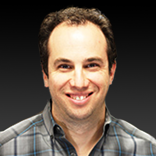 A man with a beard and plaid shirt smiling. A man with a beard and plaid shirt smiling.