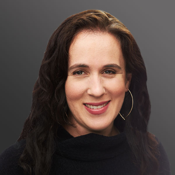 A woman with long hair and wearing black is smiling.