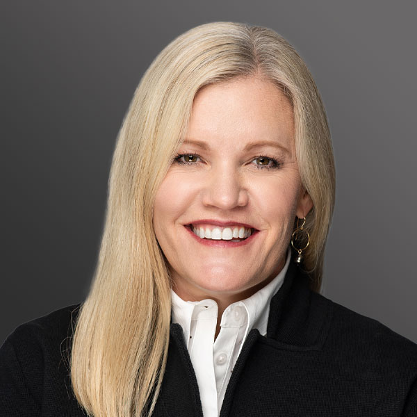 A woman with long blonde hair wearing a black jacket.