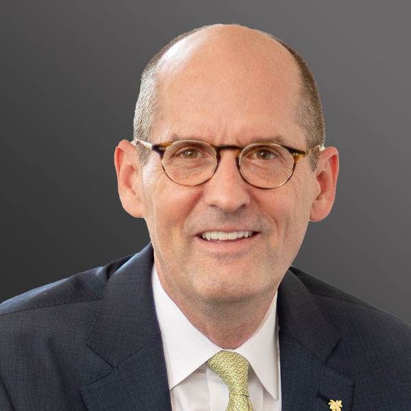A man with glasses and bald head wearing a suit.