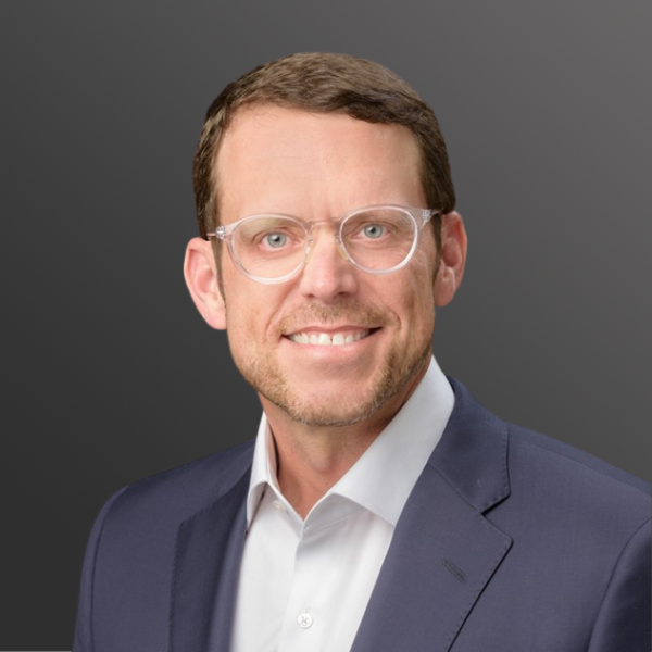 A man in a suit and glasses smiling for the camera. A man in a suit and glasses smiling for the camera.