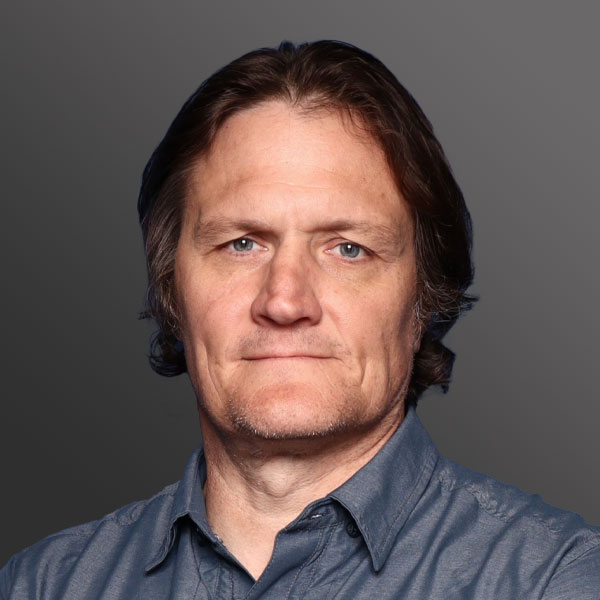 A man with long hair and wearing a blue shirt.