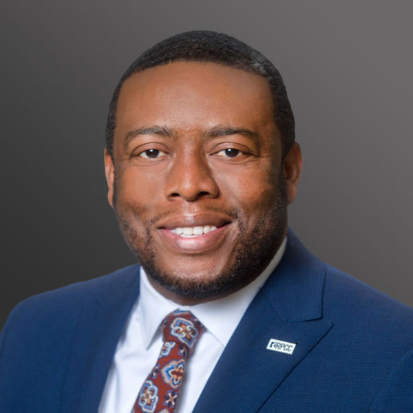 A man in a suit and tie smiling for the camera.