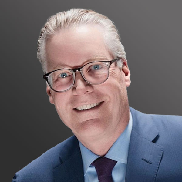 A man in a suit and glasses smiling for the camera.