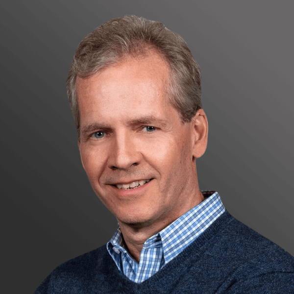 A man with grey hair and blue sweater.