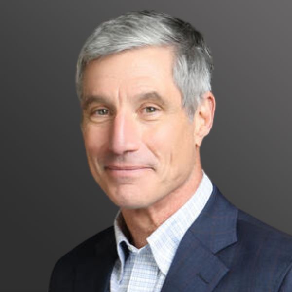 Man in suit with gray hair smiling.