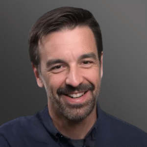 A man with a beard and mustache smiling for the camera.