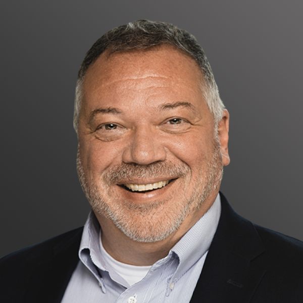 Smiling man in suit against gray background.