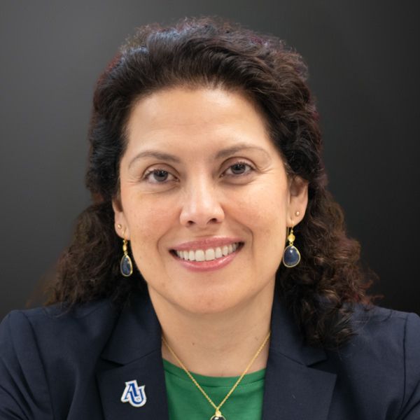 Smiling person with curly hair and earrings.