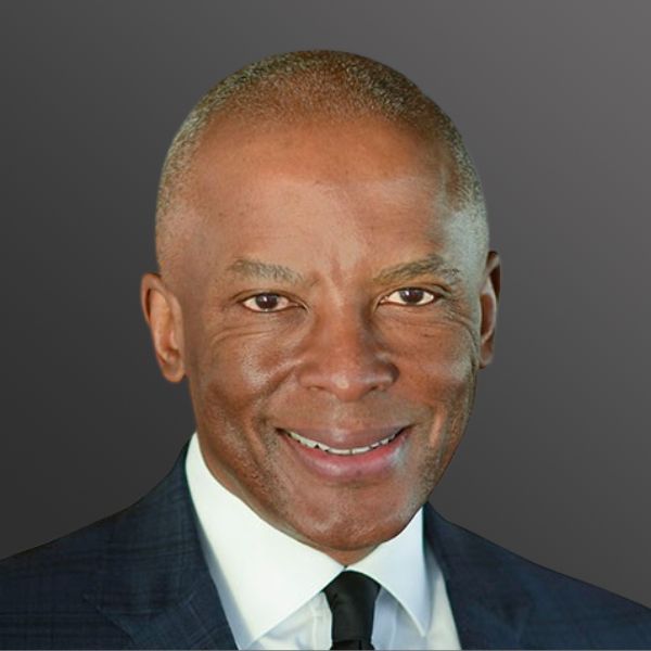 Smiling man in suit against gray background.