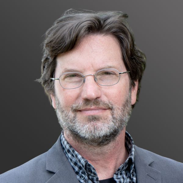 Man with glasses and beard, wearing suit.