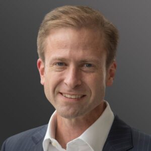 Man smiling in a suit and shirt.