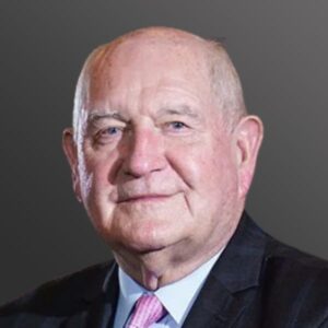 Elderly man in suit with gray background.